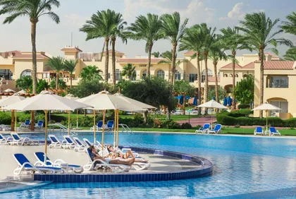 Garden pool terrace with palms, loungers and low-rise guest buildings