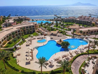 Aerial view over the resort's lagoon pools, palm gardens and the Red Sea beyond