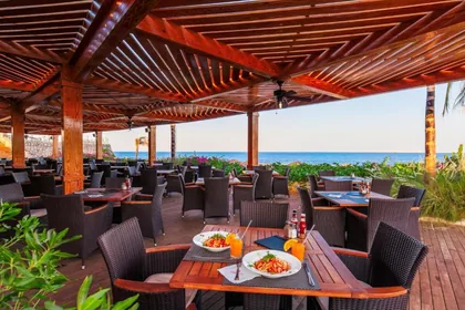 Shaded wooden beachfront restaurant terrace set for lunch