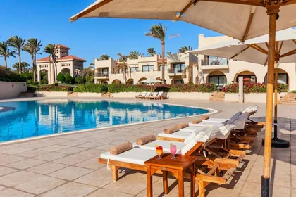Sun loungers and a parasol on the pool terrace beside the guest buildings