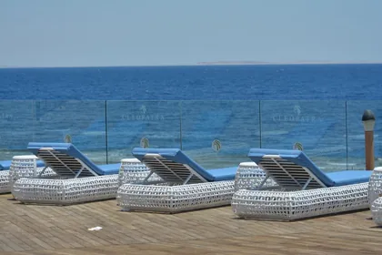 Cushioned loungers on a glass-edged deck looking out over the water
