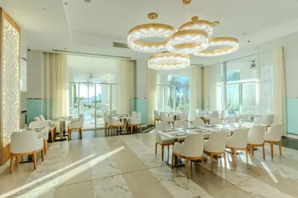 Dining room lit by ring chandeliers and opening to the terrace