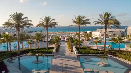 Palm-lined pool axis running from the resort toward the sea